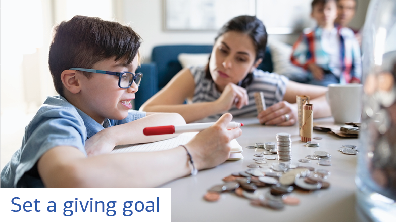 A young boy wearing glasses sits at a table with a woman who could be his mother. He has a notepad and a pen in hand. In front of him is a table full of change. In the background sits a young boy and a man on a couch. Text reads: Set a giving goal