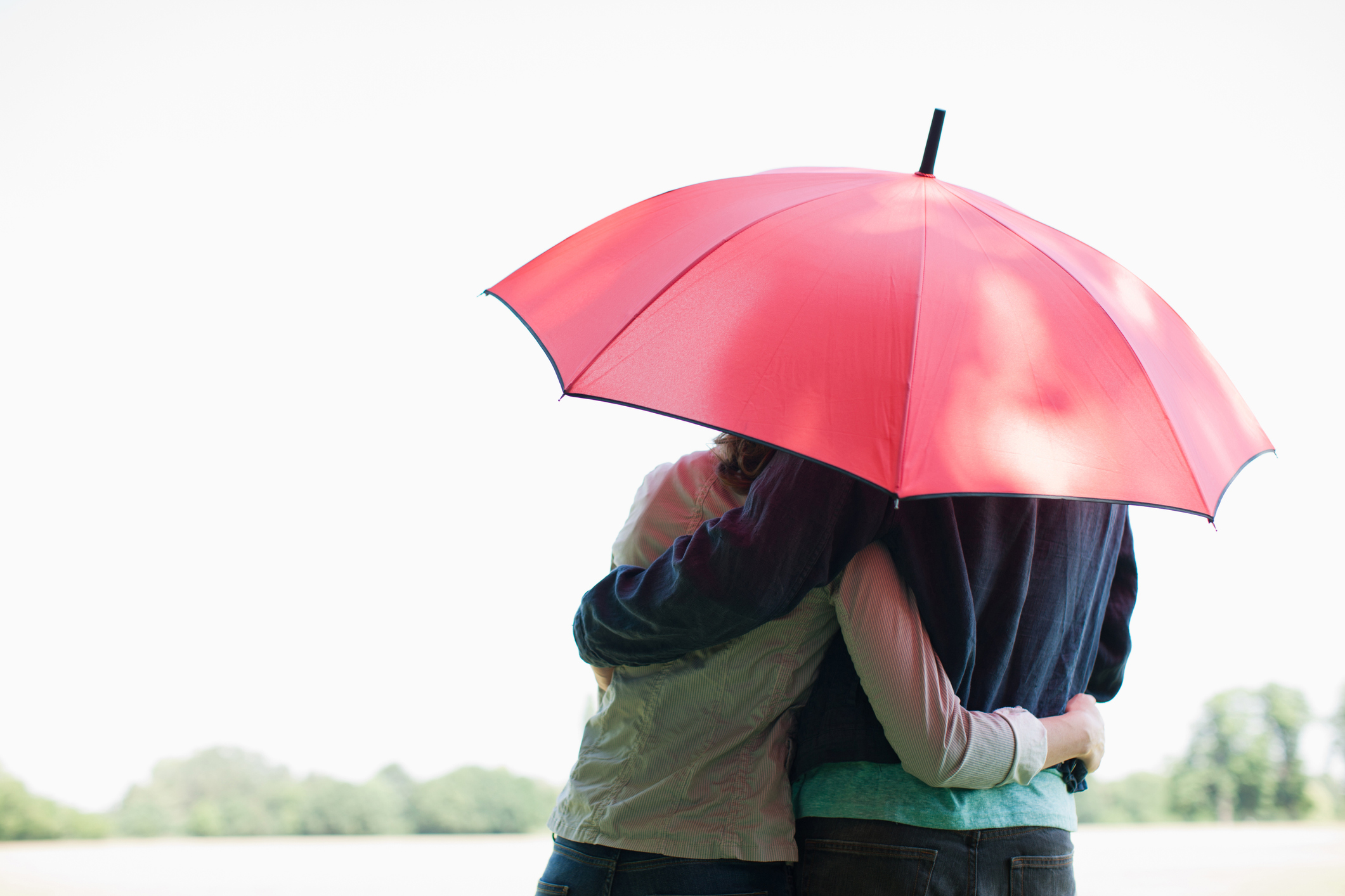 Couple hugging under an umbrella.