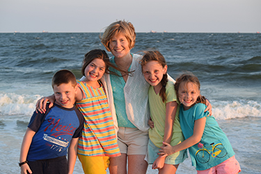A photo of Erin with her four children at the beach.