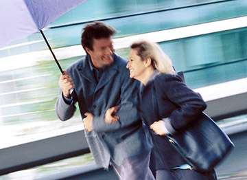 Article Image - A man and woman walking together under an umbrella. Explore how to prepare for 4 retirement risks.