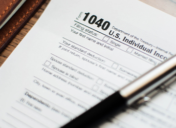 Article Image - A pen on top of a 1040 tax form. Become a tax-aware investor with these strategies.