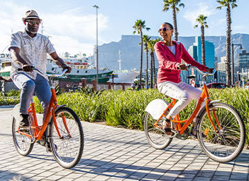Article Image - A couple riding bikes on a boardwalk. Tips on leisure spending during retirment.