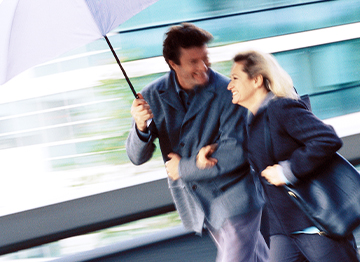 Article Image - A couple walking under a purple umbrella. Learn how to limit retirement retirement risks.