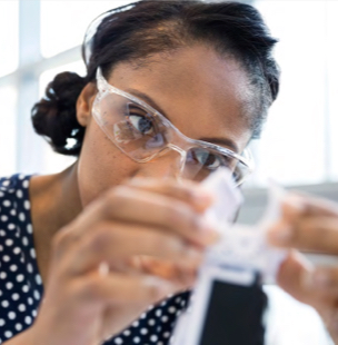 woman with safety glasses looking at medical instrument
